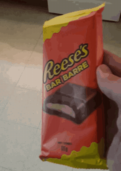 A Person Is Holding A Bag Of Reese 'S Bar GIF