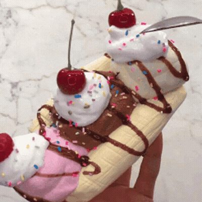 A Person Is Holding A Banana Split With Whipped Cream And Sprinkles GIF