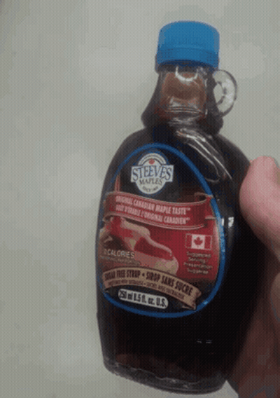 A Person Is Holding A Bottle Of Steeva 'S Maple Syrup In Their Hand GIF