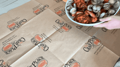 A Person Is Holding A Bowl Of Crawfish On A Crab Place Bag GIF