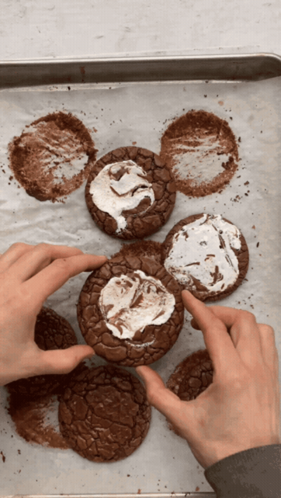 A Person Is Holding A Brownie With Marshmallow Frosting On It GIF