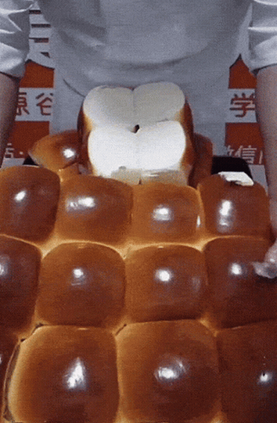 A Person Is Holding A Bunch Of Bread In Front Of A Sign That Says ' Chinese ' On It GIF