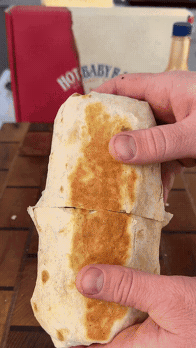 A Person Is Holding A Burrito In Front Of A Hot Baby Box GIF