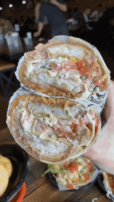 A Person Is Holding A Burrito That Has A Lot Of Toppings GIF