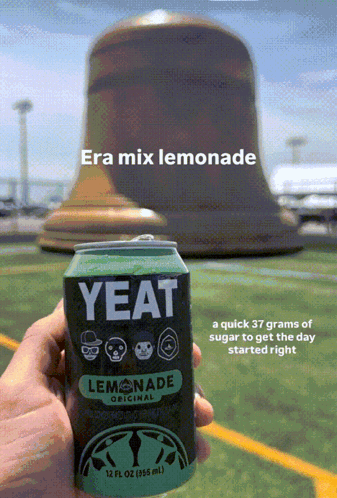 A Person Is Holding A Can Of Yeat Lemonade In Front Of A Large Bell GIF