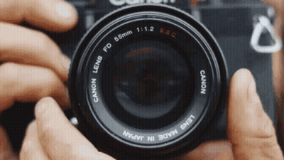 A Person Is Holding A Canon Camera Lens In Their Hands GIF