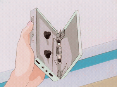 A Person Is Holding A Cassette Tape In Their Hand GIF