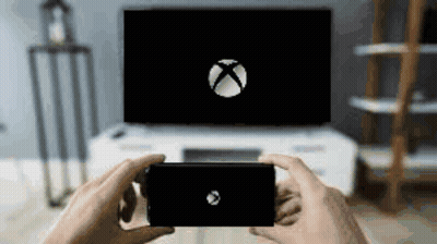 A Person Is Holding A Cell Phone In Front Of An Xbox Logo On A Television . GIF