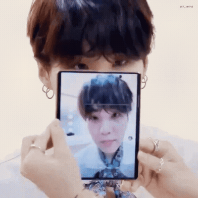 A Person Is Holding A Cell Phone In Front Of Their Face And Taking A Picture Of A Person . GIF