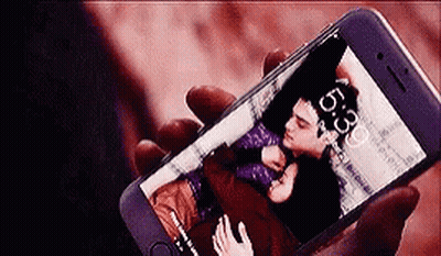 A Person Is Holding A Cell Phone With A Picture Of A Man And A Woman On The Screen . GIF