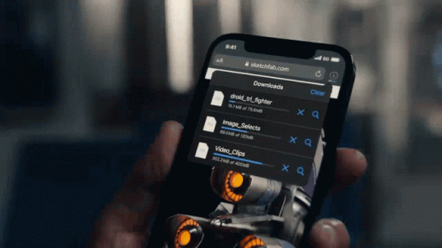 a person is holding a cell phone with sketchfab.com on it