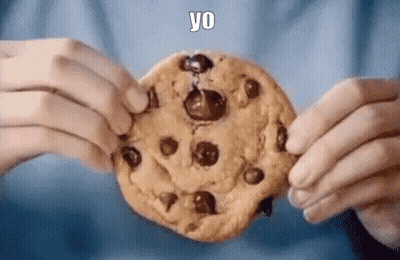 A Person Is Holding A Chocolate Chip Cookie In Their Hands With A Bite Taken Out Of It . GIF