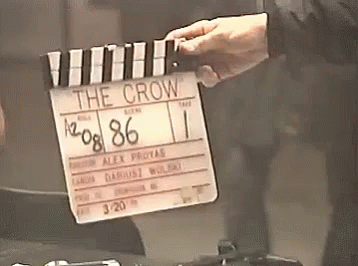 A Person Is Holding A Clapper Board That Says " The Crow " GIF