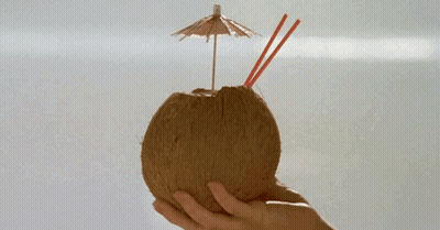 A Person Is Holding A Coconut With Straws And An Umbrella On Top GIF