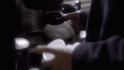 A Person Is Holding A Cup In Their Hand In Front Of A Stove . GIF