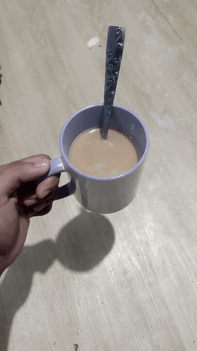 A Person Is Holding A Cup Of Coffee With A Spoon Sticking Out Of It GIF