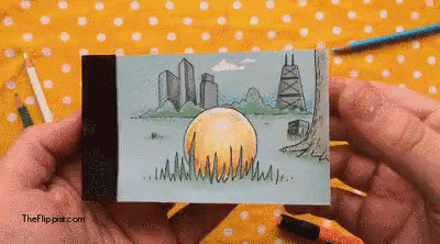 A Person Is Holding A Drawing Of A City Skyline With The Website Theflippat.com Visible In The Corner GIF