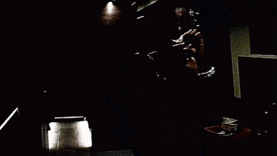 A Person Is Holding A Fan In Front Of A Couch In A Dark Room . GIF