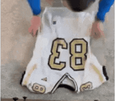 A Person Is Holding A Football Jersey With The Number 83 On It GIF