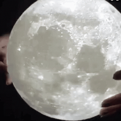 A Person Is Holding A Giant Moon In Their Hands . GIF