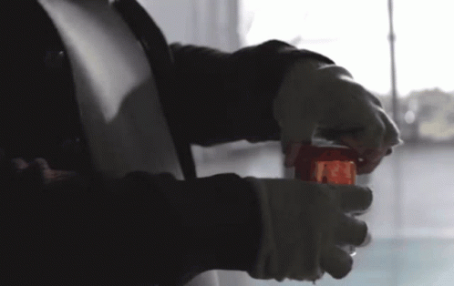 A Person Is Holding A Glass With A Red Liquid Inside Of It GIF