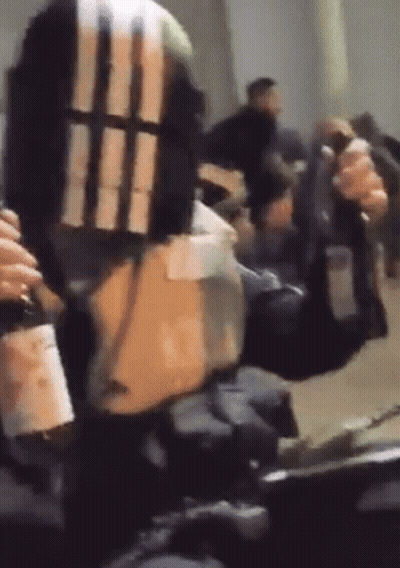 A Person Is Holding A Gun And A Bottle Of Wine In Their Hand . GIF