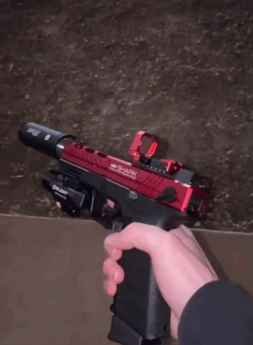 A Person Is Holding A Gun In A Warehouse GIF
