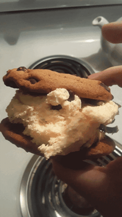 A Person Is Holding A Half Eaten Cookie With Whipped Cream And Chocolate Chips GIF