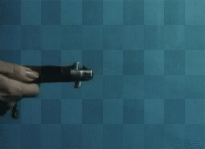 A Person Is Holding A Knife In Their Hand Against A Blue Wall . GIF