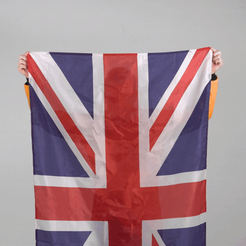 A Person Is Holding A Large British Flag In Their Hands GIF