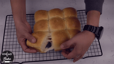 A Person Is Holding A Loaf Of Bread That Says Knead And Bake GIF
