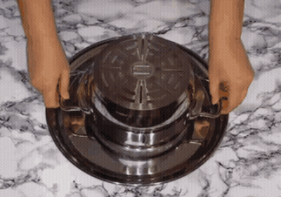 A Person Is Holding A Metal Tray With A Lid On Top Of It GIF