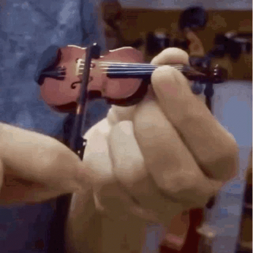 A Person Is Holding A Miniature Violin In Their Hand GIF