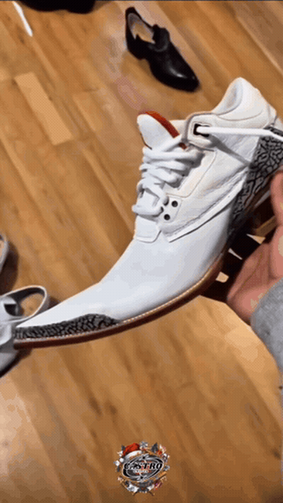 A Person Is Holding A Pair Of White Shoes On A Wooden Floor With The Word Castro On The Bottom Right GIF