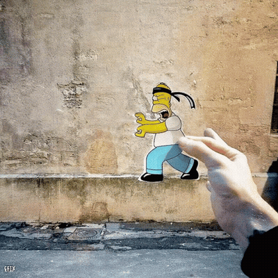 A Person Is Holding A Paper Cut Out Of Homer Simpson In Front Of A Wall That Says Efly GIF