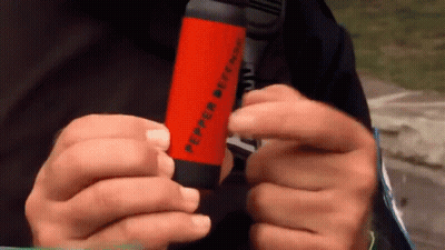 A Person Is Holding A Pepper Spray Bottle In Their Hands . GIF