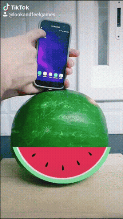 A Person Is Holding A Phone Over A Watermelon GIF