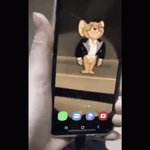 A Person Is Holding A Phone With A Jerry Mouse On The Screen GIF