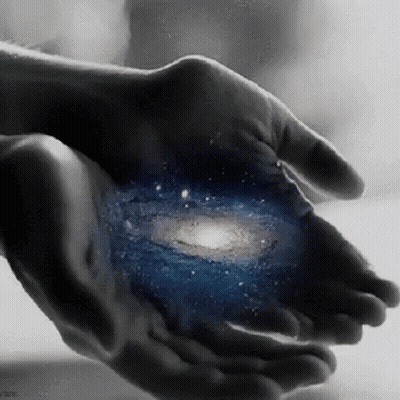 A Person Is Holding A Picture Of The Galaxy In Their Hands . GIF