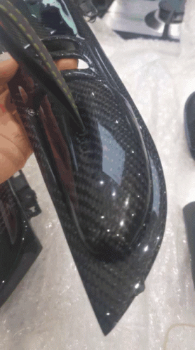A Person Is Holding A Piece Of Black Carbon Fiber GIF