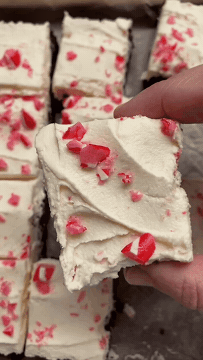A Person Is Holding A Piece Of Cake With Candy Canes On Top GIF