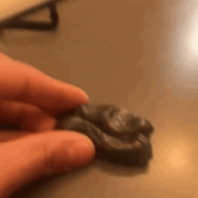 A Person Is Holding A Piece Of Clay In Their Hands . GIF