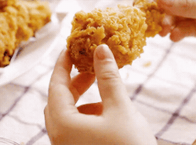 A Person Is Holding A Piece Of Fried Chicken Between Their Fingers . GIF