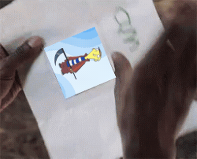 A Person Is Holding A Piece Of Paper That Has A Picture Of A Cartoon Character On It GIF