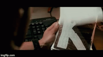 A Person Is Holding A Piece Of Paper That Says K On It GIF