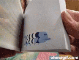 A Person Is Holding A Piece Of Paper With A Fish On It And The Website Ohmagif.com Is Visible In The Corner GIF