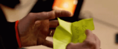 A Person Is Holding A Piece Of Yellow Paper That Says ' No ' On It GIF