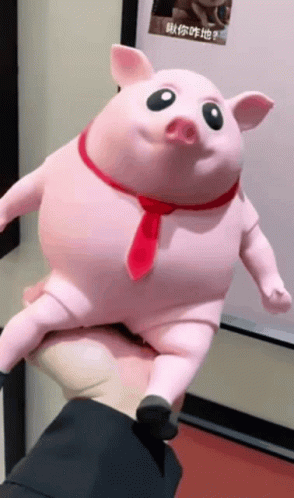 A Person Is Holding A Pink Pig With A Red Tie Around Its Neck GIF