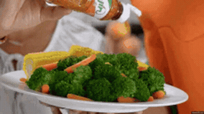 A Person Is Holding A Plate Of Broccoli Carrots And Corn GIF
