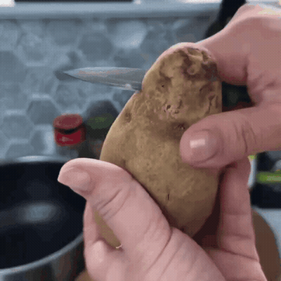 A Person Is Holding A Potato In Their Hands With A Knife In It GIF